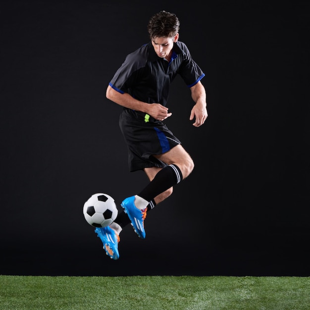 Photo field soccer player and man with jump for game training and action for practice with ball black background athlete and person with kick for football talent and fitness for sport outdoor and goal