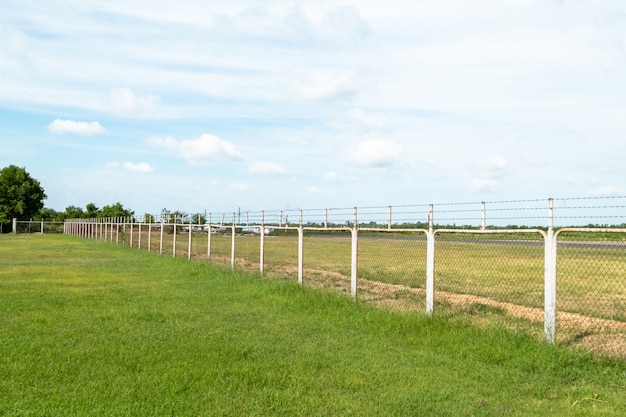 Field with green grass and metal fence