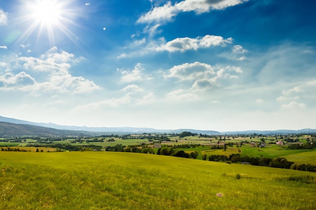 a field with a sun shining on the sky