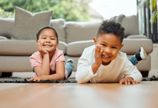 A fierce protector, big sis. Portrait of two young siblings lying on the floor together at home.