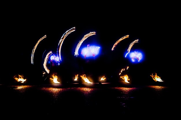 Fiery pieces of a fire show against a dark sky and thunderstorms