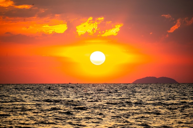 fiery sunset over ocean with vibrant shades of orange and red painting sky sun sets dramatically casting warm glow on dark waters below creating breathtaking reflection of natures stunning canvas