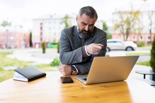 Fifty serious male businessman working on a laptop in a street cafe