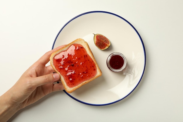 Fig jam plate and toaster bread in hand on white background top view