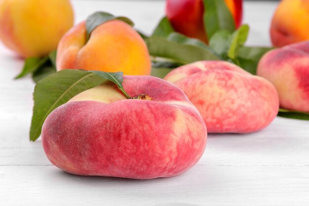 Figs peach close-up and in the background peaches of different varieties on a white wooden background