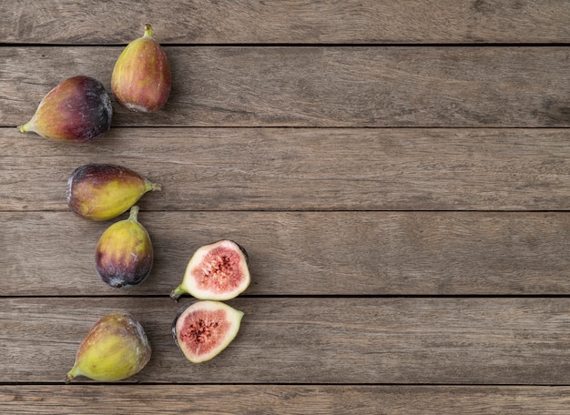 Photo figs with cut fruit over wooden table with copy space.