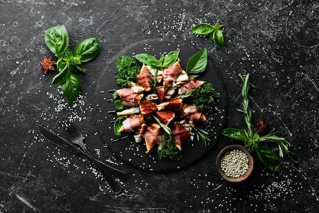 Figs with prosciutto and blue cheese and basil on a black stone plate Food Top view Free space for your text