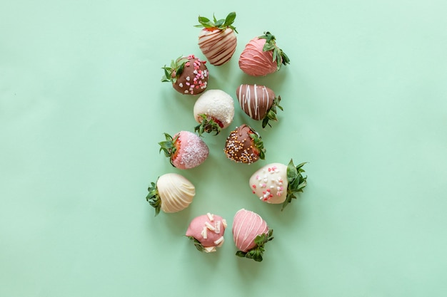 Figure eight made up of handmade chocolate covered strawberries with different toppings on green background