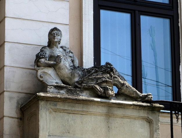 Figure of a girl lying on vacation Stone statue on the old building