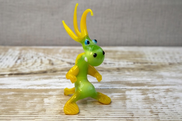 Figurine of dragon from glass on rough wooden background