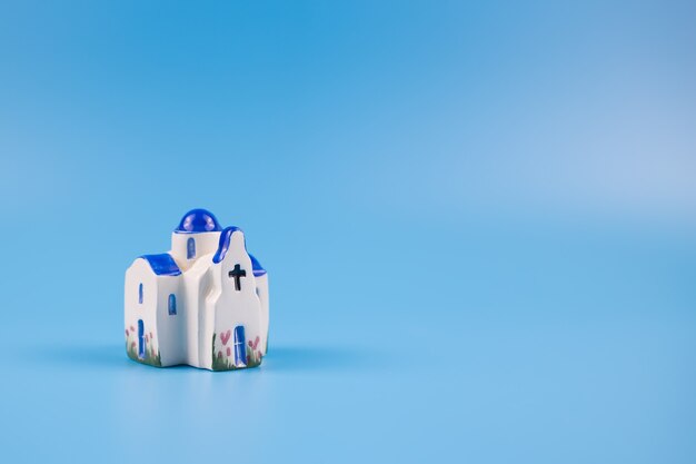 Figurine of a greek chapel, on a blue background. Postcard, travel concept.