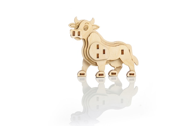 Figurine of a toy wooden cow on a white background with reflection.