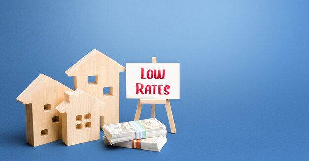 Figurines of houses and an easel with low rates. Low demand for real estate and housing