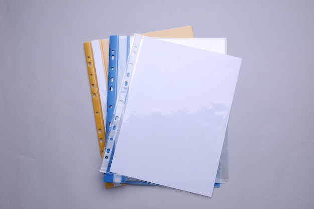 File folders with punched pockets and paper sheets on light grey background flat lay