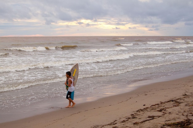 Filipino kid with surf board on the beach