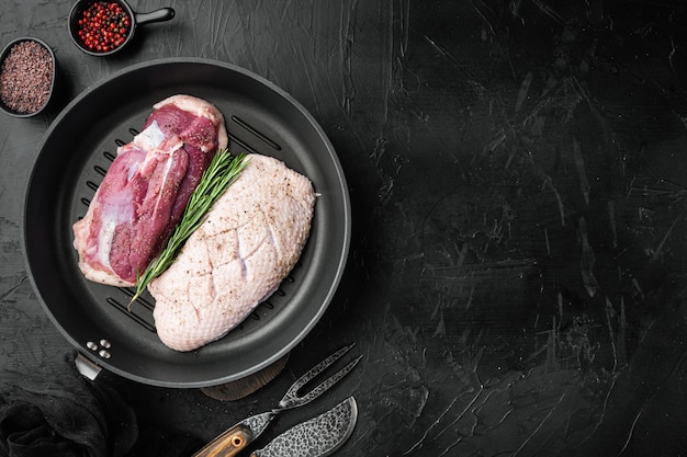 Fillet of duck uncooked raw meat set on frying cast iron pan on black stone table top view flat lay