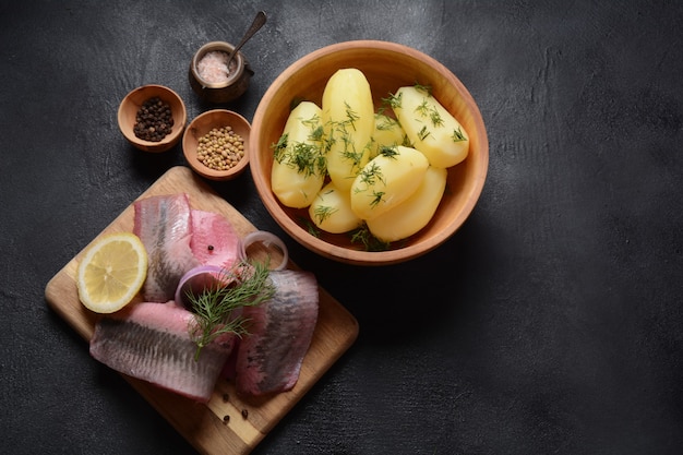 Fillet of Herring fish  on wooden board  with pepper herbs red onion and lemon