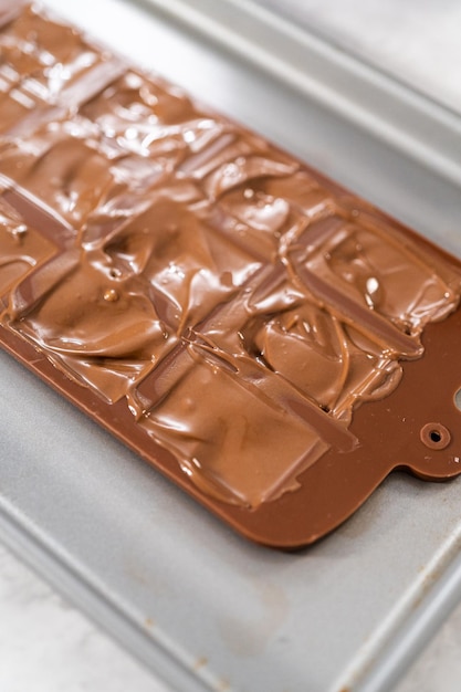 Filling chocolate silicone mold with melted dark chocolate to prepare gourmet mini chocolates with sprinkles