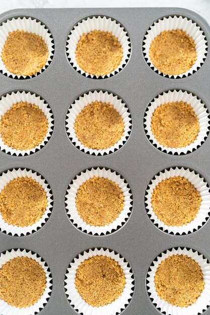 Filling cupcake liners with graham crackers to baking s'mores cupcakes.