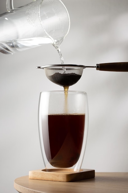 Filtering tea in cup on wooden table