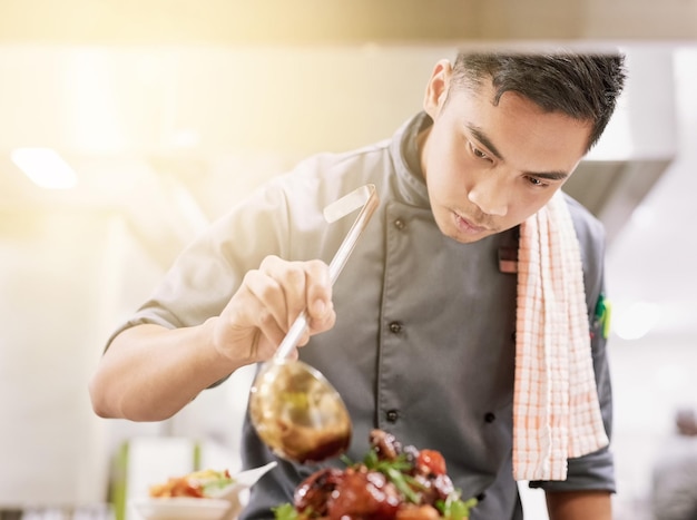 The final touch Cropped shot of a young male chef cooking in his kitchen