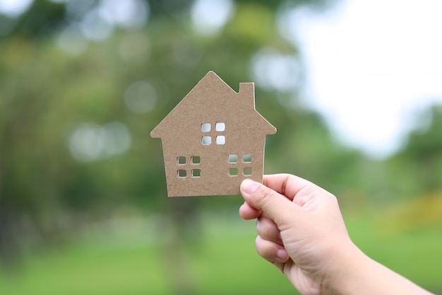 Finance and Banking concept, Woman hand holding model house on natural