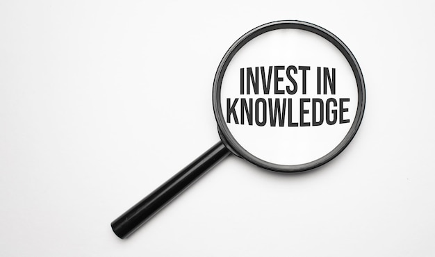 Finance and economics concept. Magnifier on a white background, inside the text is written Invest In Knowledge