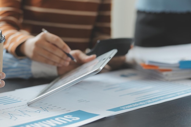 Financial analysts analyze business financial reports on a digital tablet planning investment project during a discussion at a meeting of corporate showing the results of their successful teamwork