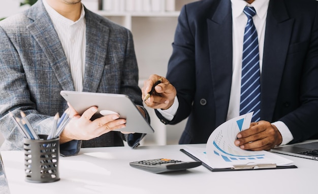 Financial analysts analyze business financial reports on a digital tablet planning investment project during a discussion at a meeting of corporate showing the results of their successful teamwork