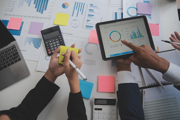 Financial analysts analyze business financial reports on a digital tablet planning investment project during a discussion at a meeting of corporate showing the results of their successful teamwork