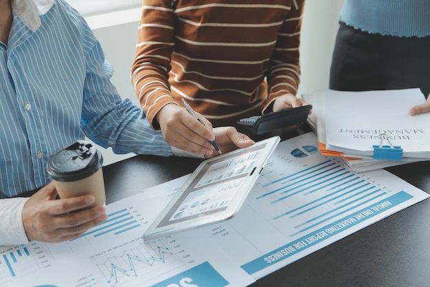 Financial analysts analyze business financial reports on a digital tablet planning investment project during a discussion at a meeting of corporate showing the results of their successful teamwork