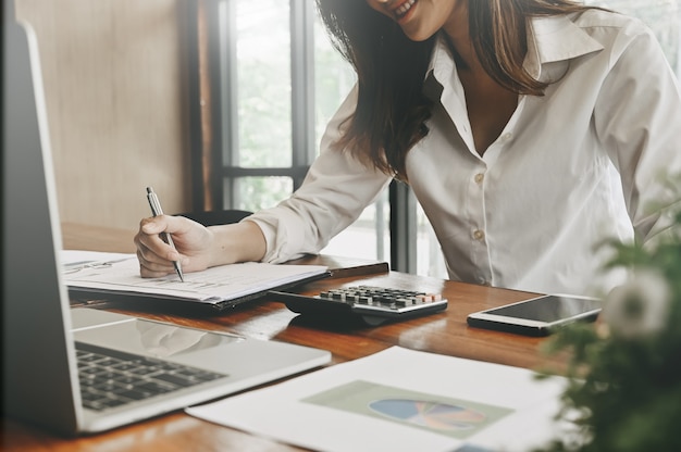 Financial home planning, Woman working on notebook paper with office finance supplies on desk.