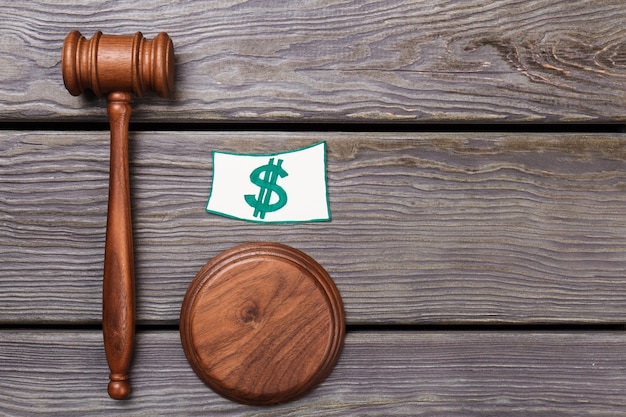 Photo financial justice concept. wooden justice hammer and dollar sign. top view gavel on the table.