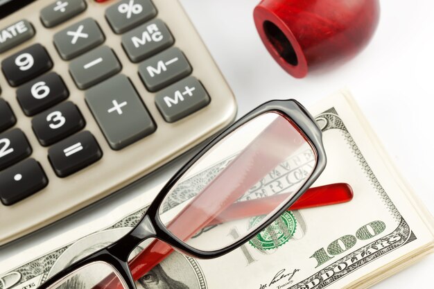 Financial Literacy. Closeup Pen, calculator, cash and glasses.