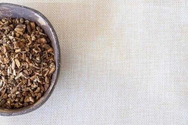 Finely chopped dried burdock root in a natural plate on a linen background Copy space top view