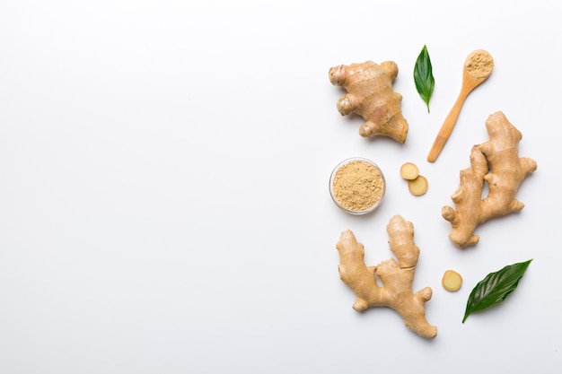 Finely dry Ginger powder in bowl with green leaves isolated on colored background top view flat lay