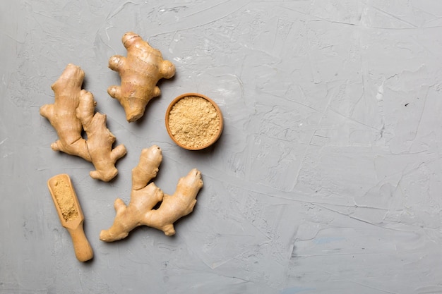 Finely dry Ginger powder in bowl with green leaves isolated on colored background top view flat lay