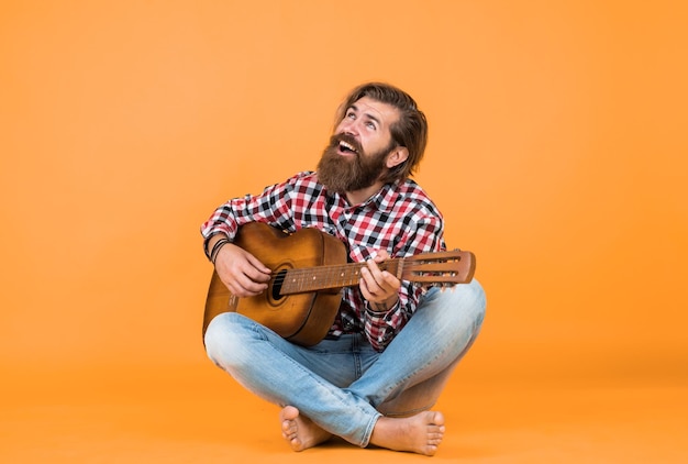 Fing the melody play string musical instrument professional caucasian musician guitarist hipster man playing acoustic guitar country music style man wearing checkered shirt and holding guitar