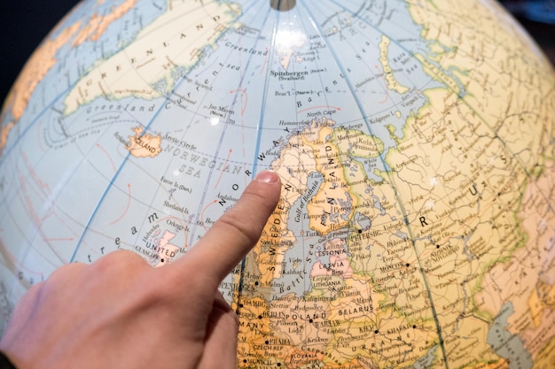 Finger pointing on world ball for planning travel trip