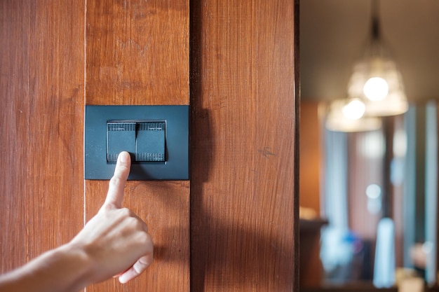 Finger turn on or off on light switch on wall at home Energy Saving power electrical and lifestyle concepts