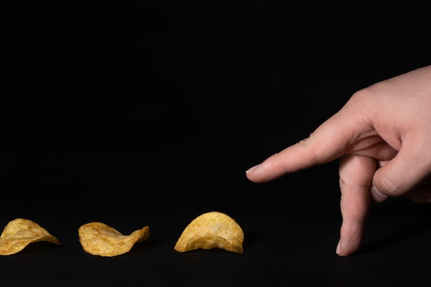 Fingers go for chips Chips track on black background