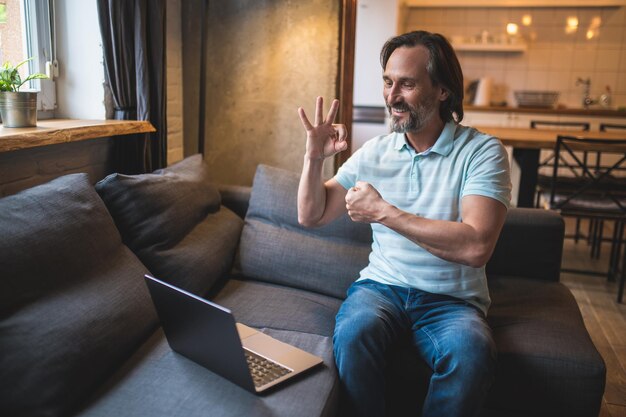 Fingers language. A man having a video call and using fingers language