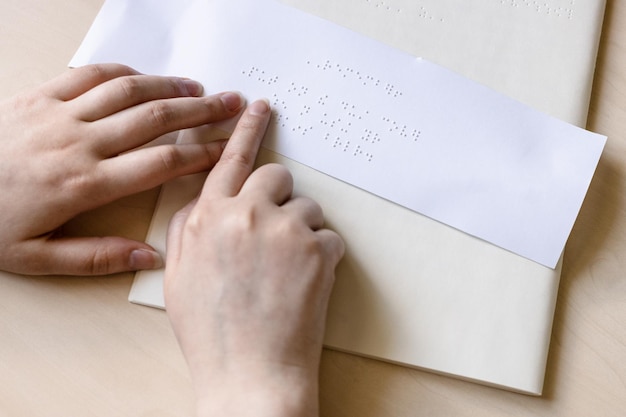 Fingertip of blind woman reads note in braille