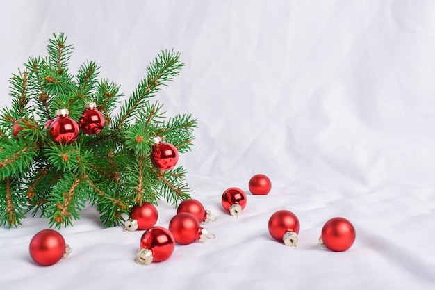 A fir branch with glass balls on a white background. Merry Christmas. Festive background. A place to copy.