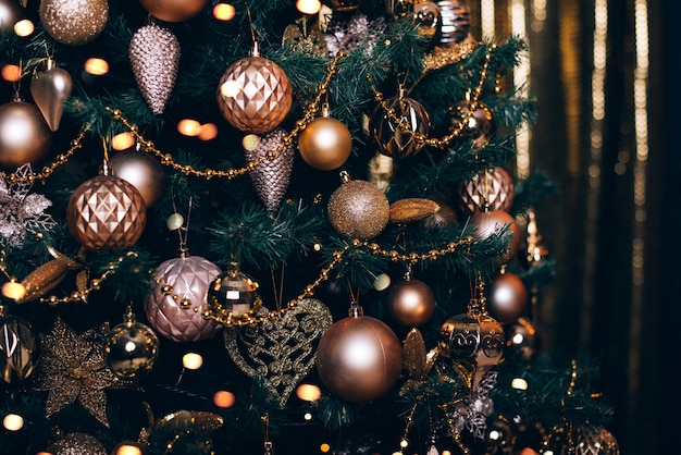 Fir branch with golden balls and festive lights on the dark background with sparkles.