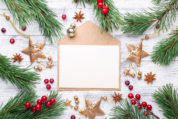 Fir branches, gifts and an envelope on a light wooden background