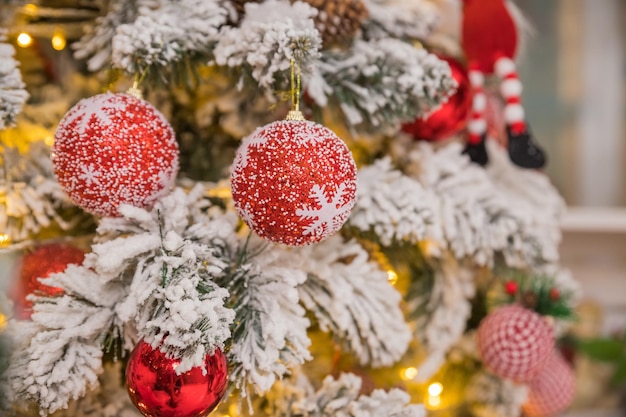 Fir tree background and festive decorations with snow blurred sparking glowing Happy New Yearholidays decoration red and white baubles hanging on a Christmas tree