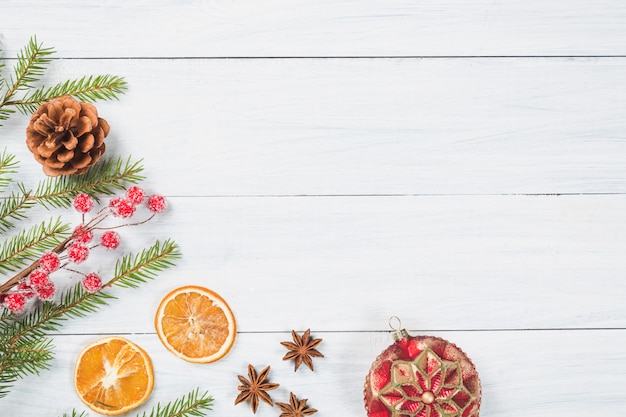  Fir tree branches with dried orange, anise stars, christmas ball and cone on white wooden background. 