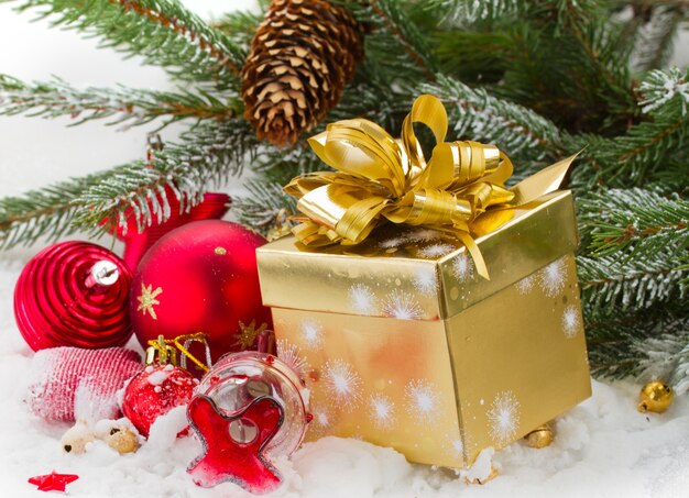 Fir tree and red christmas decorations and gift box on white snow