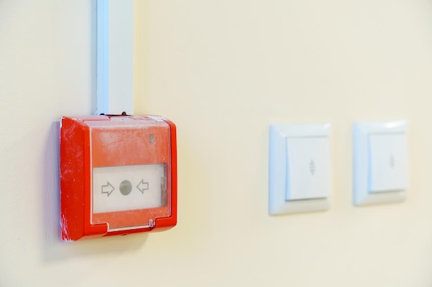 Fire alarm and light switch on the wall Equipment for fire notification in emergency situations Red fire alarm switch on the wall